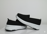Black slip-on sneakers with white soles